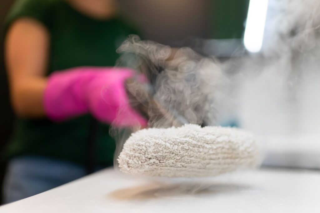 Woman cleaning kitchen furniture with a steam cleaner close up